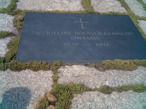 Gravestone of Jacqueline Bouvier Kennedy Onassis, marked with her name and years 1929-1994, surrounded by greenery.