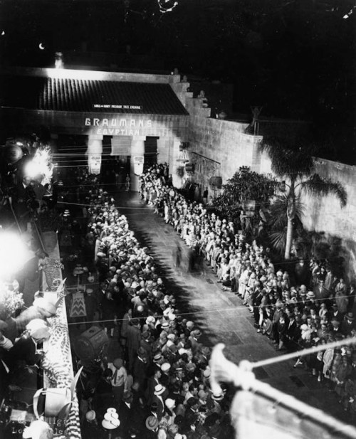 A historic black-and-white photo of a large crowd gathered outside Grauman's Egyptian Theatre at night.