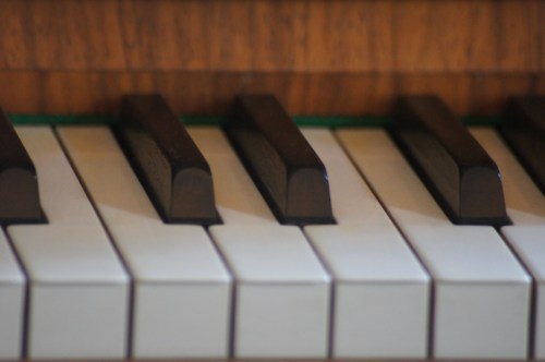Close-up of piano keys, showcasing the contrast between black and white keys on a wooden surface.