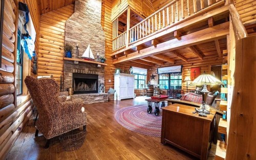 Cozy log cabin interior with a stone fireplace, wooden beams, and a warm, inviting atmosphere.