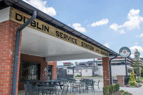 Exterior of Dublin Service Station and Garage, featuring a covered patio with tables and a vintage sign.