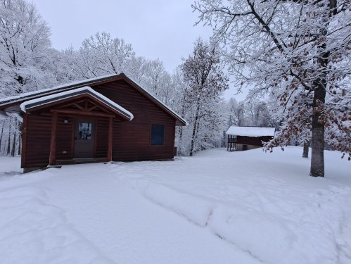 A cozy wooden cabin surrounded by snow-covered trees and a winter landscape.