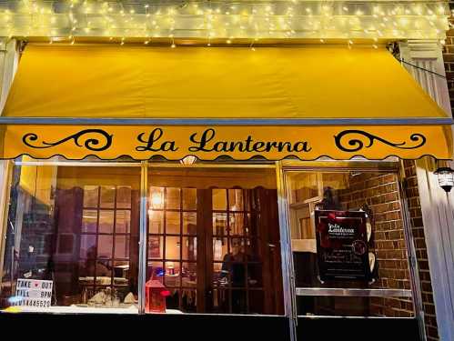 A cozy restaurant exterior with a yellow awning reading "La Lanterna," illuminated by string lights.