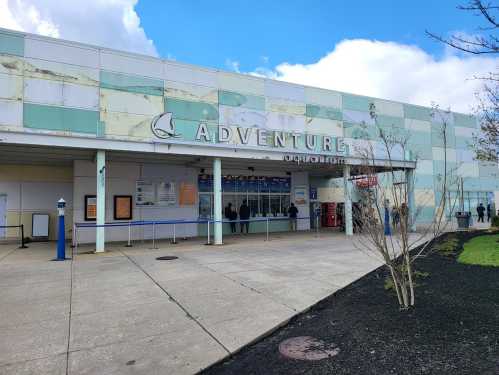 Entrance of Adventure Aquarium with a cloudy sky and visitors waiting outside.