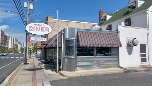 A classic diner with a metal exterior and awning, featuring a sign that reads "Angelo's Diner" and a parking area.