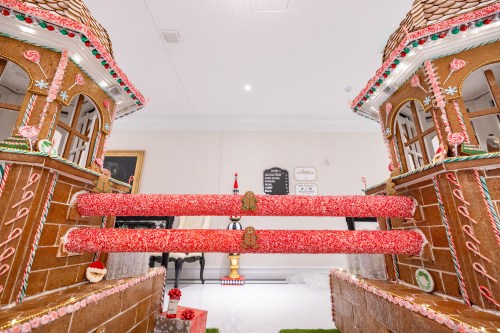 A festive gingerbread house with candy decorations and two towers, featuring red candy cane railings.