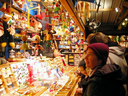 A festive market stall filled with colorful toys and decorations, with people browsing and admiring the items.