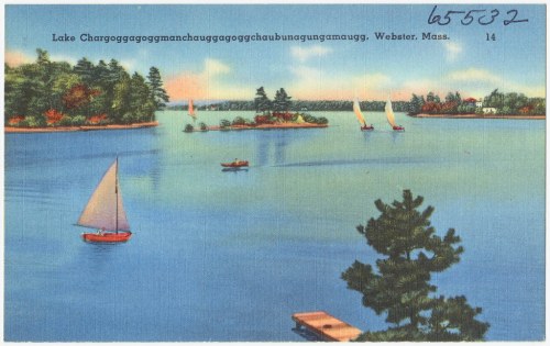 A serene lake scene with sailboats and a lush shoreline, featuring trees and distant islands, in Webster, Massachusetts.