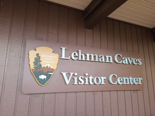 Sign for Lehman Caves Visitor Center, featuring the National Park Service logo and mountain imagery.