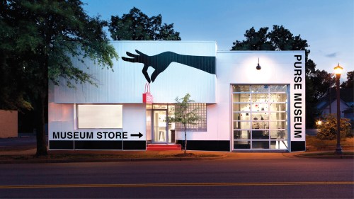 Exterior of the Purse Museum, featuring a large hand silhouette and a sign pointing to the museum store.
