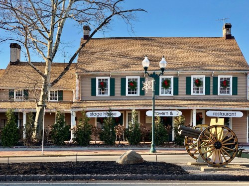 Historic building with festive decorations, featuring a cannon in front and signs for a tavern and restaurant.