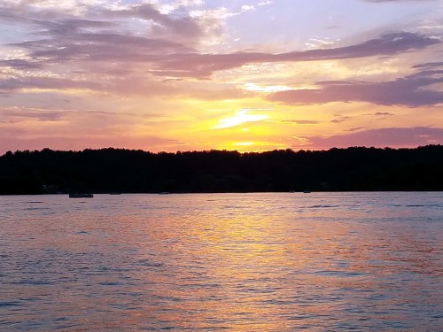 A serene sunset over a calm lake, with vibrant orange and purple hues reflecting on the water.