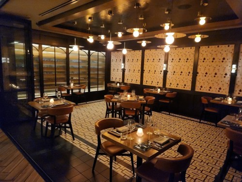 Elegant restaurant interior with dim lighting, wooden tables, and stylish decor, creating a cozy atmosphere.