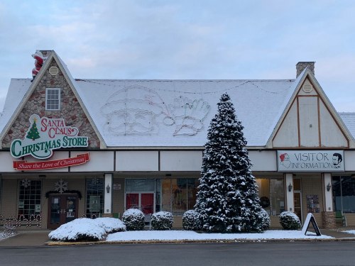 A festive Christmas store with snow-covered decorations and a large Santa mural on the roof.
