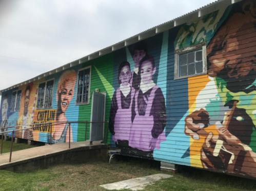 Colorful mural on a building featuring children and community themes, with vibrant artwork and diverse expressions.