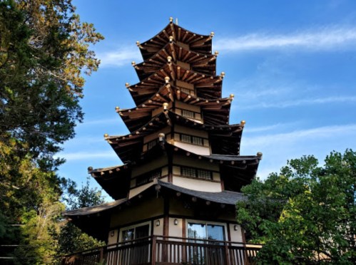 A tall, multi-tiered pagoda surrounded by trees under a clear blue sky.