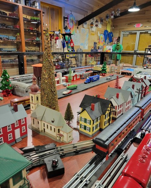 A model train display featuring colorful buildings, trees, and a festive atmosphere with a train running through.