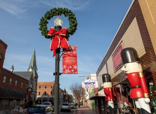 A festive street scene with a decorated lamppost, holiday wreath, and nutcracker figures in a charming town.