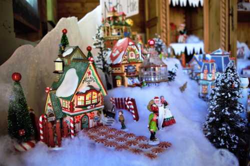 A festive miniature village scene with colorful buildings, candy canes, and snow-covered trees, evoking a holiday atmosphere.