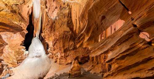 A stunning cave interior featuring intricate rock formations and stalactites illuminated by soft lighting.