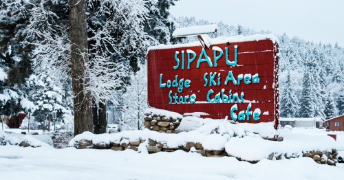 Sign for Sipapu Lodge and Ski Area, surrounded by snow-covered trees and a winter landscape.