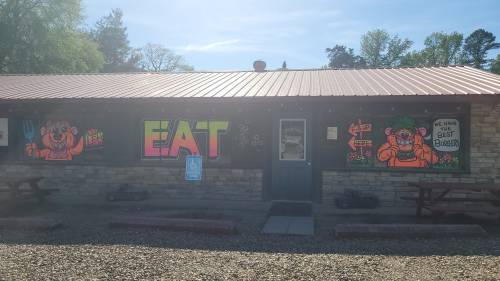 A colorful restaurant exterior with "EAT" painted on the wall and cartoon characters, surrounded by picnic tables.