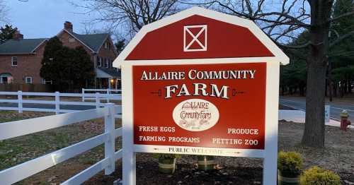 Sign for Allaire Community Farm, featuring fresh eggs, farming programs, and a petting zoo. Public welcome.