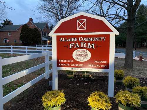 Sign for Allaire Community Farm, featuring fresh eggs, farming programs, produce, and a petting zoo. Public welcome.