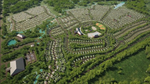 Aerial view of a large, green landscape featuring organized rows of tents, pathways, and water features.