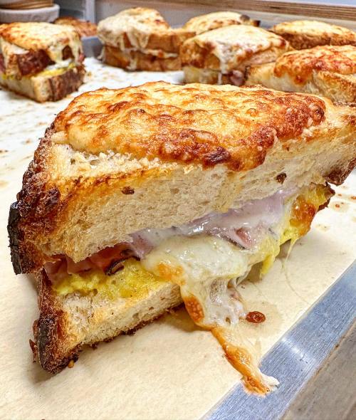 A gooey, cheesy sandwich with layers of ham and egg, nestled between golden, toasted bread.