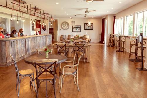 A cozy, modern café interior with wooden tables, chairs, and a bar area, featuring large windows and warm lighting.