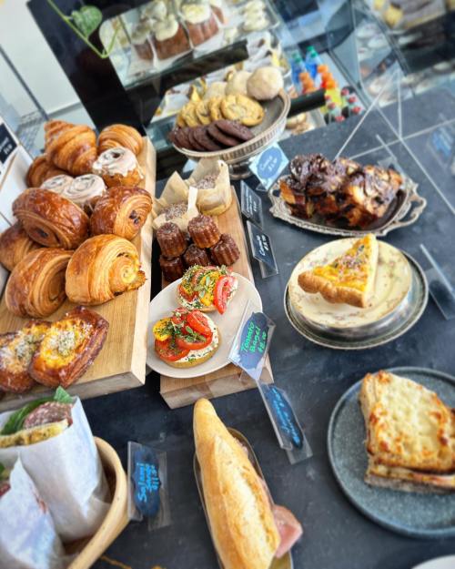 A display of assorted baked goods, including croissants, cookies, pastries, and savory dishes on wooden and ceramic plates.