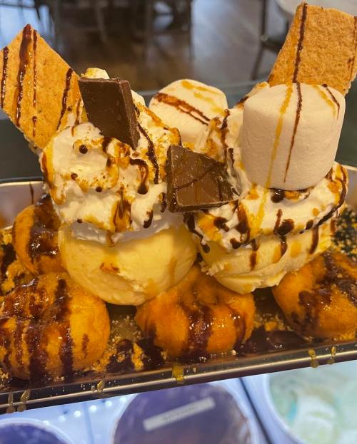 A decadent dessert with two scoops of ice cream, whipped cream, chocolate, graham crackers, and marshmallows.