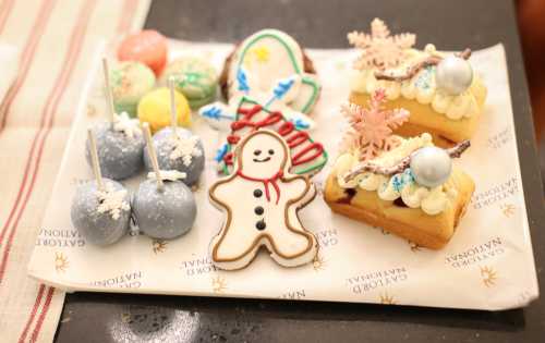 A festive platter of decorated cookies, colorful macarons, and holiday-themed desserts on a branded napkin.