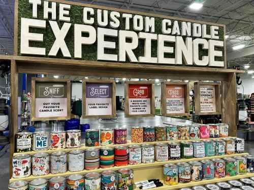 A display for a custom candle experience, featuring various candle scents and label designs for selection.