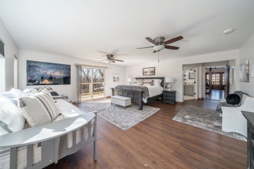 Spacious bedroom with two beds, a large window, and a view of nature, featuring modern decor and wooden flooring.