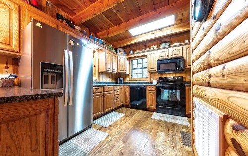 Cozy wooden kitchen with stainless steel appliances, dark countertops, and warm wood cabinetry. Bright and inviting space.