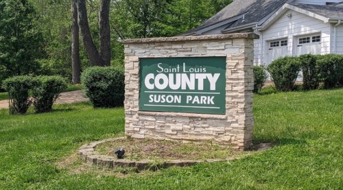 Sign for Suson Park in Saint Louis County, surrounded by greenery and landscaping.