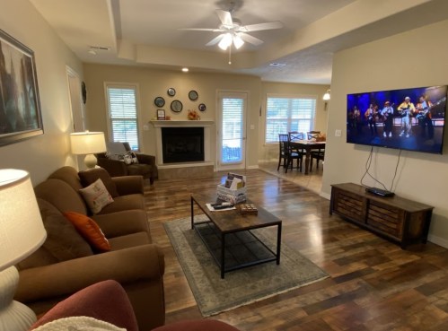 Cozy living room with a sofa, coffee table, and TV, leading to a dining area with a table and chairs.