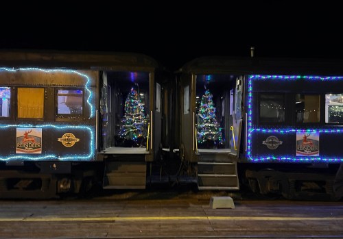 Two train cars decorated with colorful Christmas lights and small Christmas trees inside, set against a night sky.