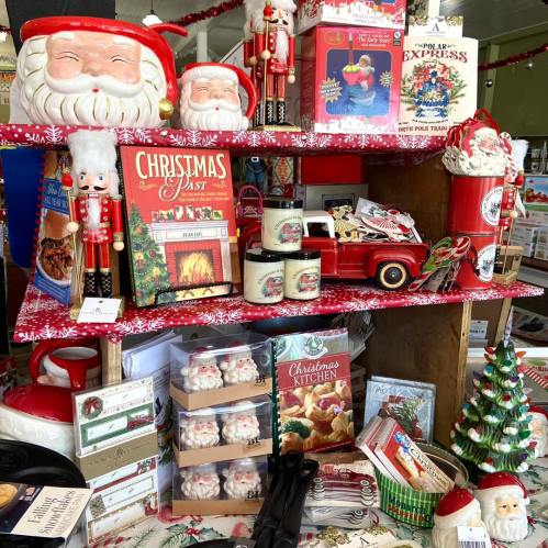 A festive display of Christmas decorations, including Santa figurines, candles, and holiday-themed books.