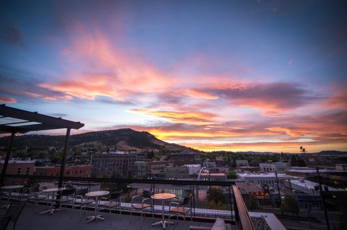 A vibrant sunset over a cityscape, with mountains in the background and colorful clouds filling the sky.