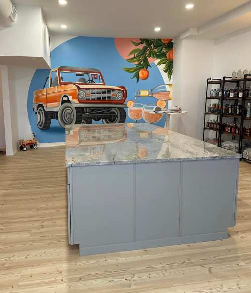 Modern kitchen with a large gray island and a colorful mural of a vintage orange truck and tropical elements on the wall.