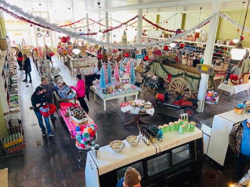 A bustling store decorated for the holidays, filled with colorful items and shoppers browsing various products.