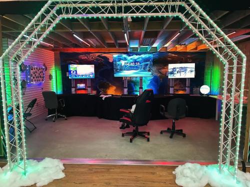 A tech setup with colorful lights, screens displaying a countdown, and chairs in a modern, festive environment.