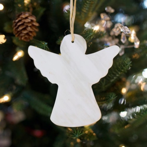A white angel ornament hanging on a Christmas tree, surrounded by pine needles and soft lights.