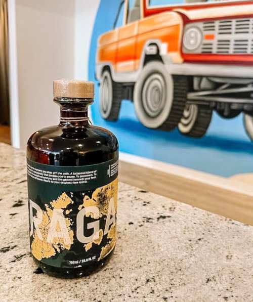 A bottle of Paga on a granite countertop, with a colorful mural of a vintage truck in the background.