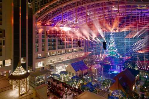 A vibrant indoor space with colorful lights and a large Christmas tree, surrounded by festive decorations and dining areas.