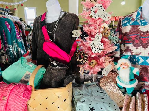 A display of colorful clothing and accessories, featuring a pink tree, a basket of clothes, and festive decorations.