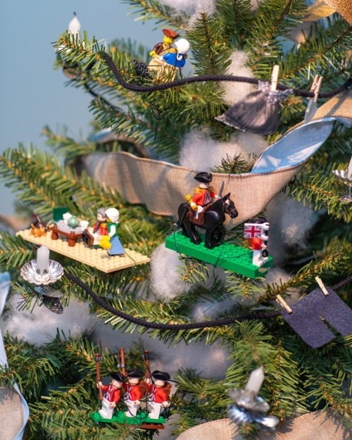 A Christmas tree decorated with LEGO figures, including soldiers, a horseman, and a festive table scene.
